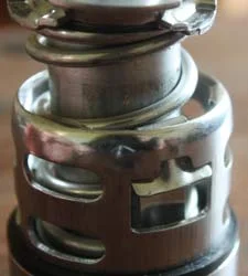 The same cage and spring even closer, showing the retaining clip on top.